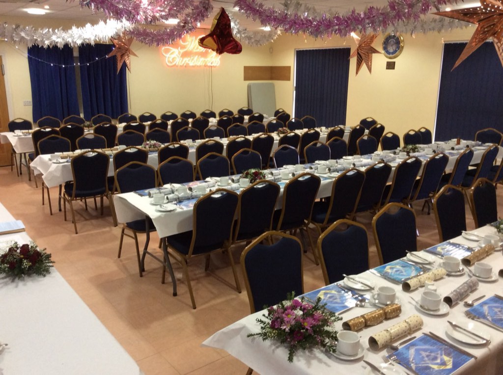 The hall laid with long tables for a Christmas dinner